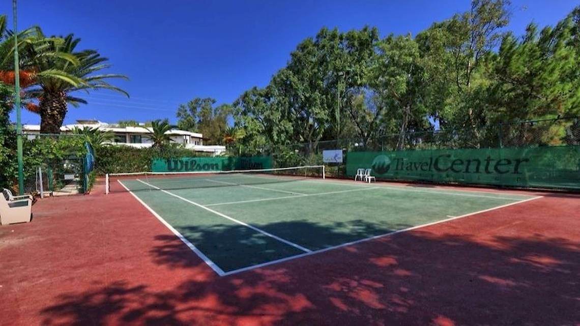 Tennisplatz im Apollonia Beach Resort & Spa mit grünem Rasen, weißen Linien und einer Wilson-Tafel.