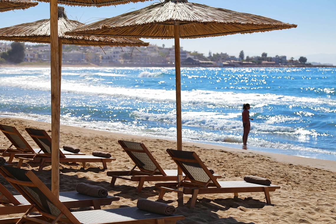 Strandszene mit Sonnenschirmen und Liegestühlen am Domes Noruz Chania, Autograph Collection
