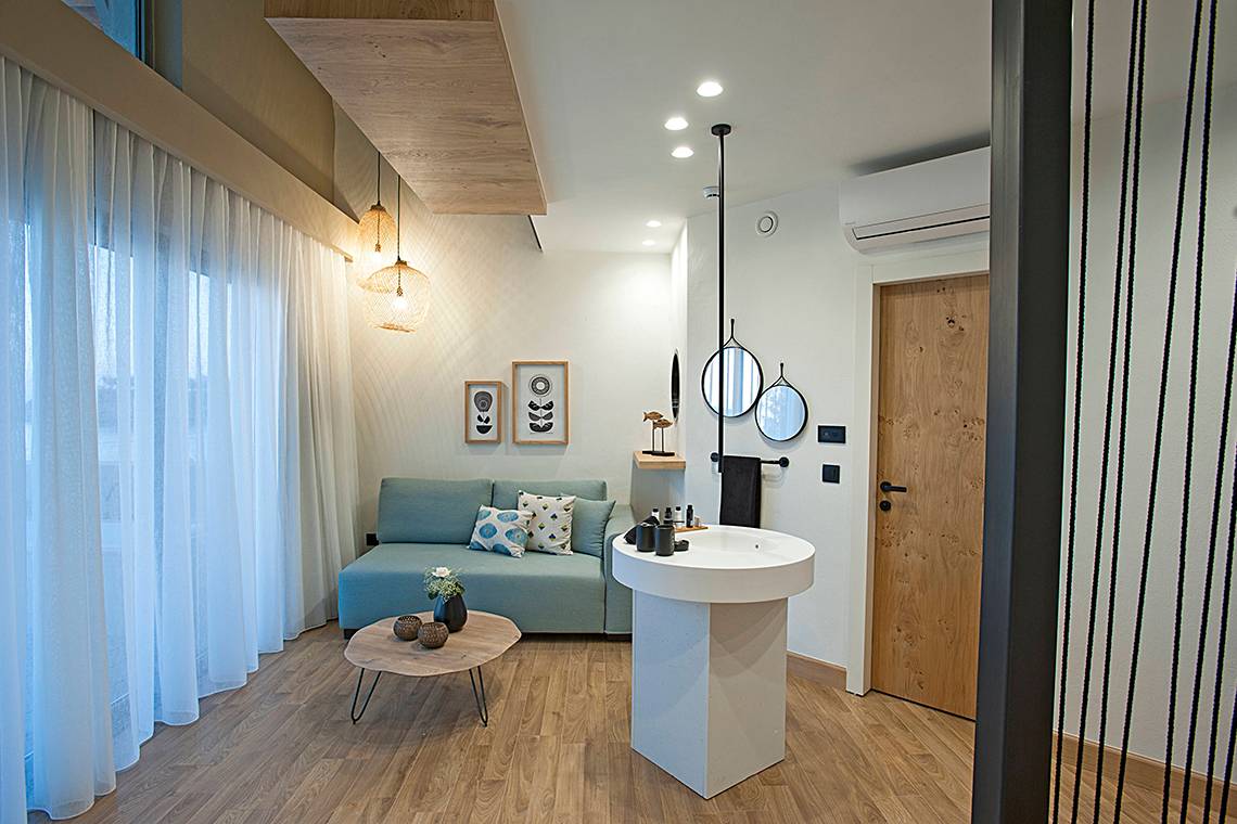Innenbereich des Domes Noruz Chania, Autograph Collection mit Sofa, Tisch und Waschbecken.