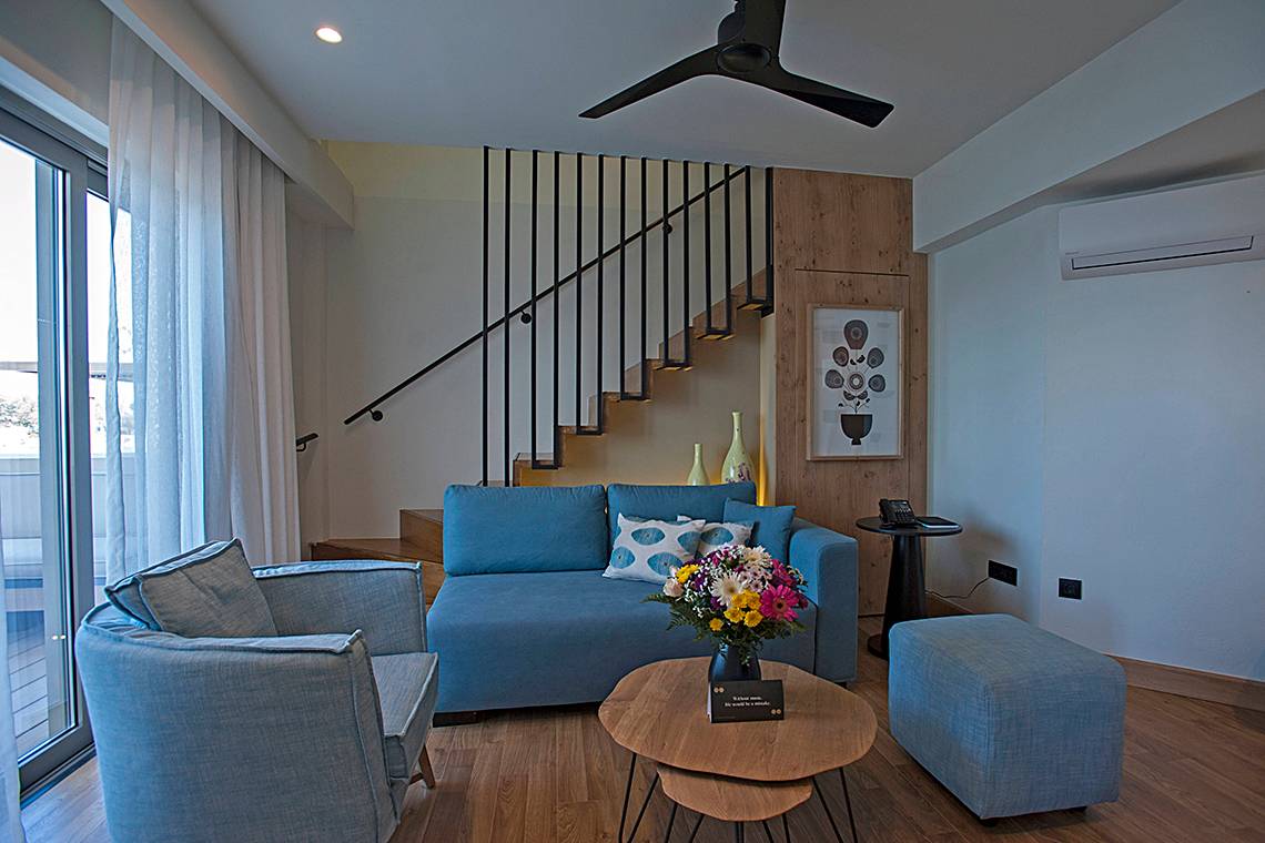 Innenbereich des Domes Noruz Chania Autograph Collection mit Wohnzimmer, Sofa, Tisch und Stairs