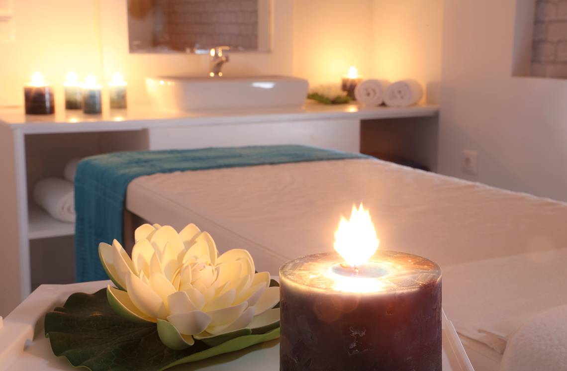 Spa-Behandlungszimmer im LABRANDA Marine Aquapark mit Bett, Kerzen und Lotusblume.