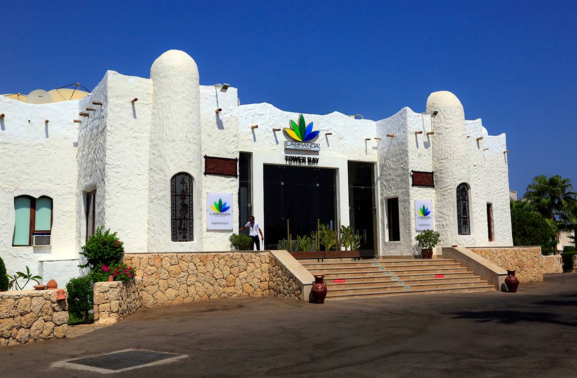 Eingang des Sharm Club Beach Resorts mit einer Person und Pflanzen davor