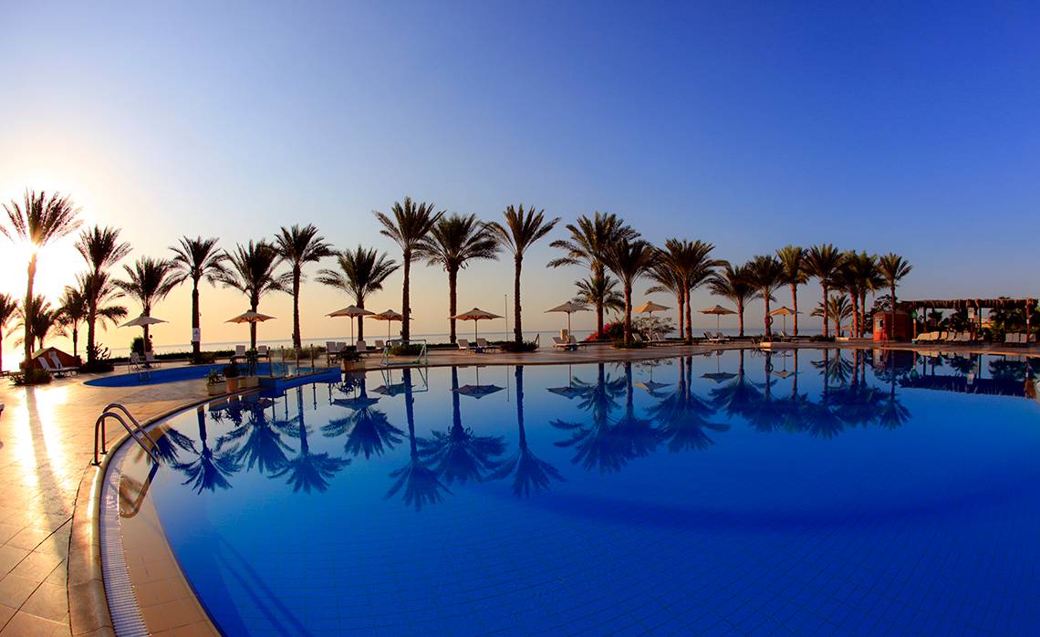 Ein Swimmingpool im Sharm Club Beach Resort mit Sonnenuntergang und Palmen