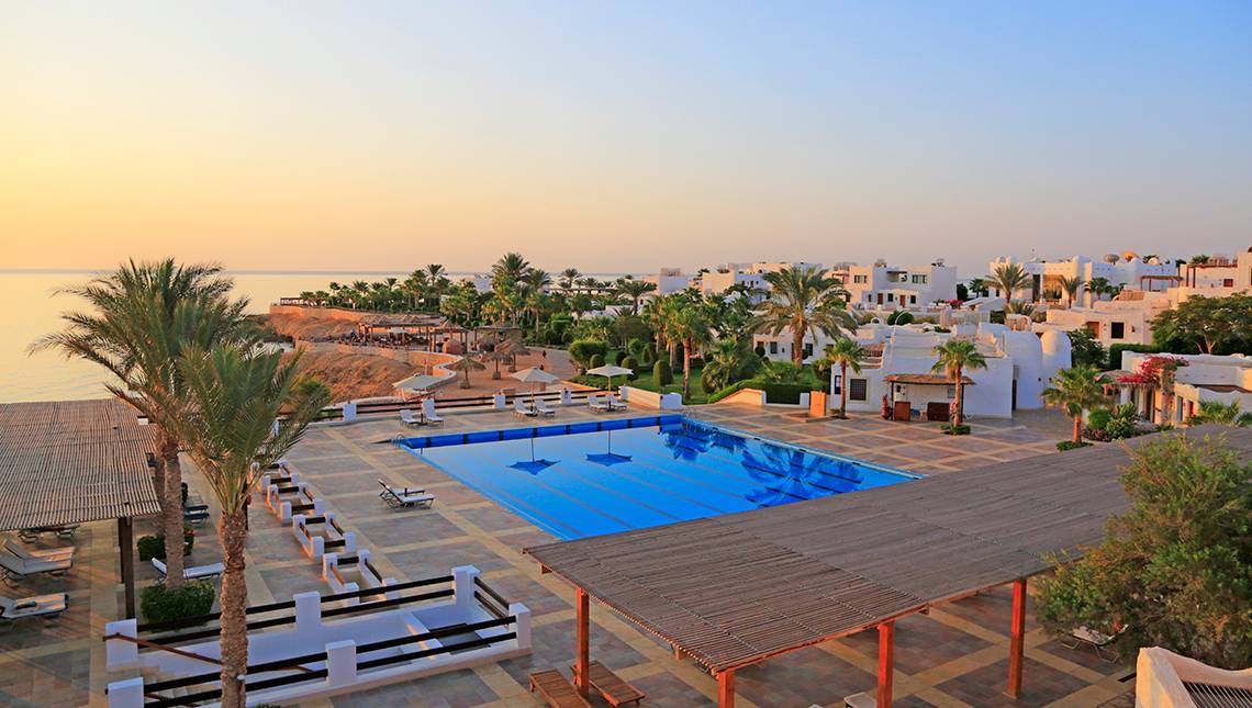 Luftaufnahme des Sharm Club Beach Resorts mit Swimmingpool, Liegen und Sonnenschirmen am Meer