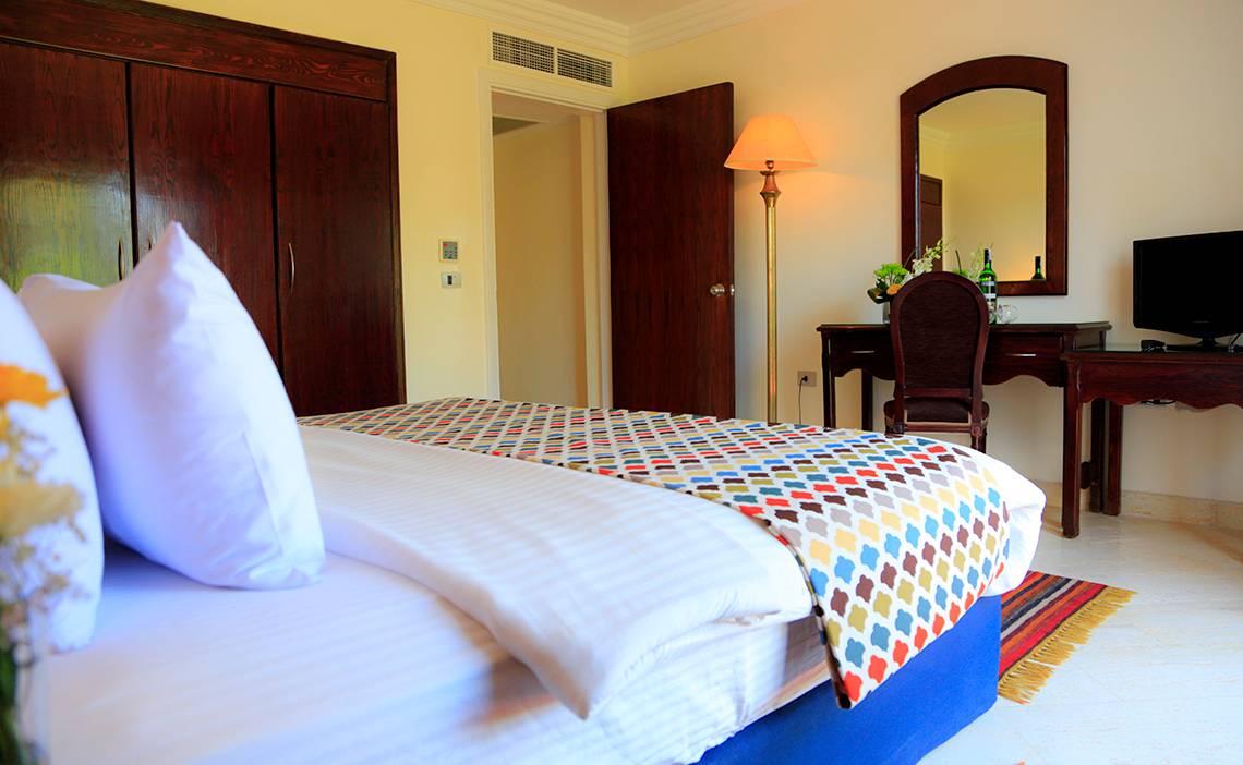 Hotelzimmer im Sharm Club Beach Resort mit Bett, Schreibtisch und Lampe.