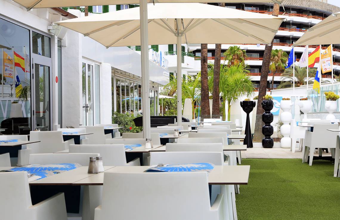 Terrasse des LABRANDA Playa Bonita Hotels mit weißen Tischen und Stühlen unter Sonnenschirmen.