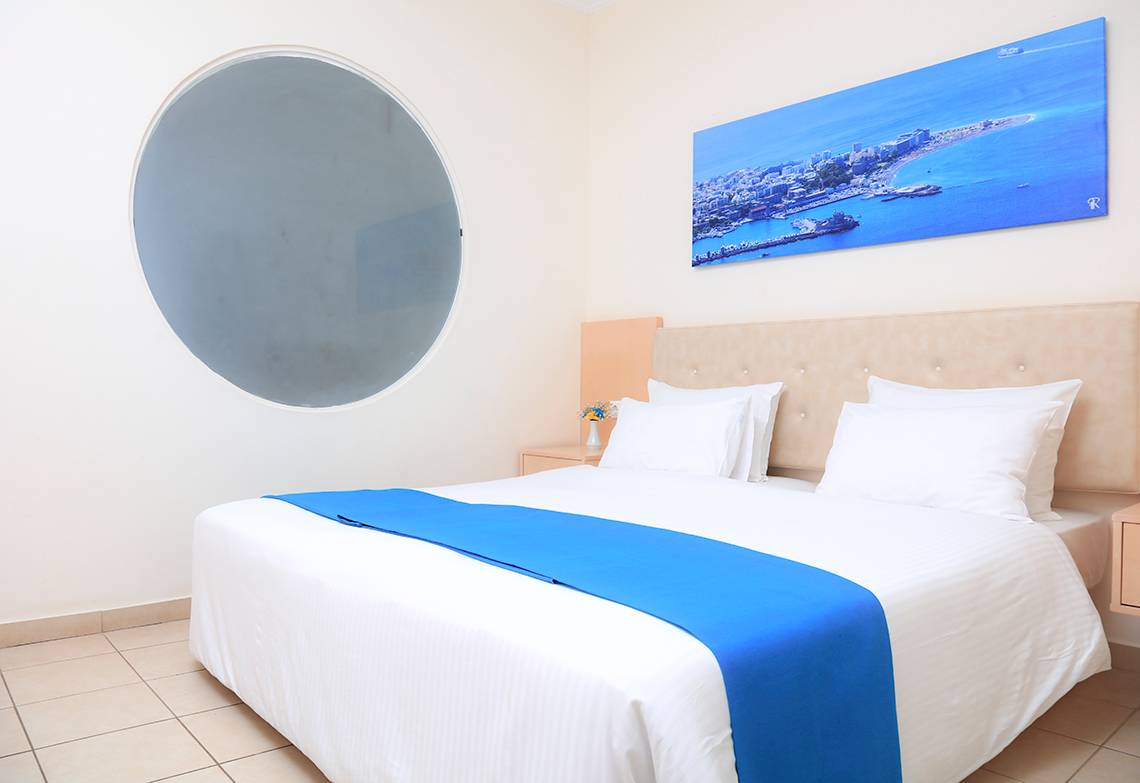 Ein geräumiges Hotelzimmer im LABRANDA Kiotari Miraluna Resort mit einem Doppelbett, einer Stadtansicht und einem runden Spiegel.