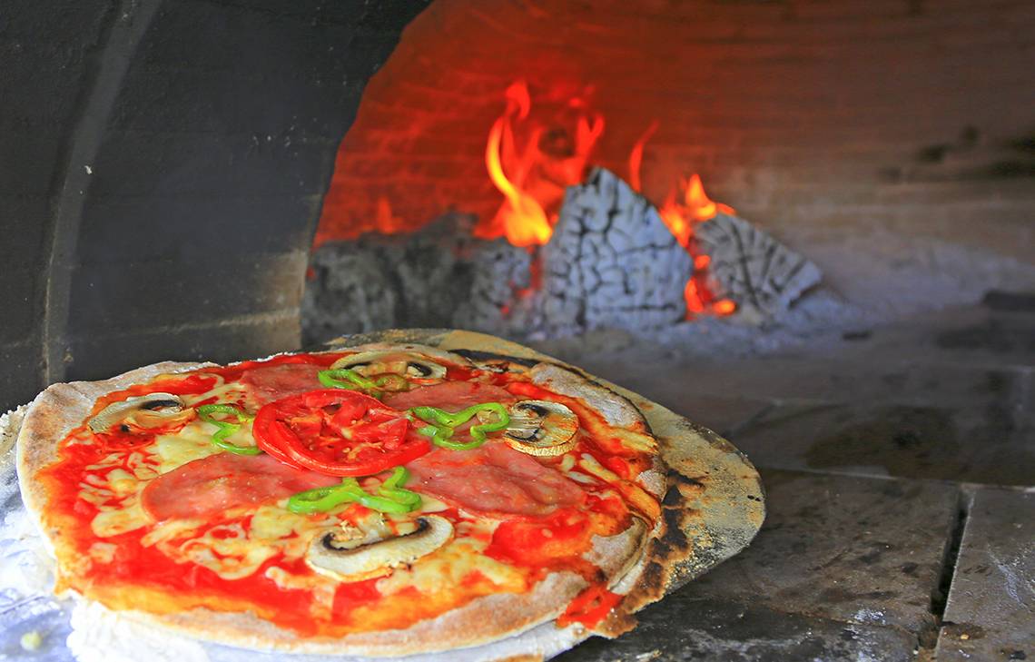 Eine Pizza mit Tomaten, Peperoni und Pilzen brät im Ofen