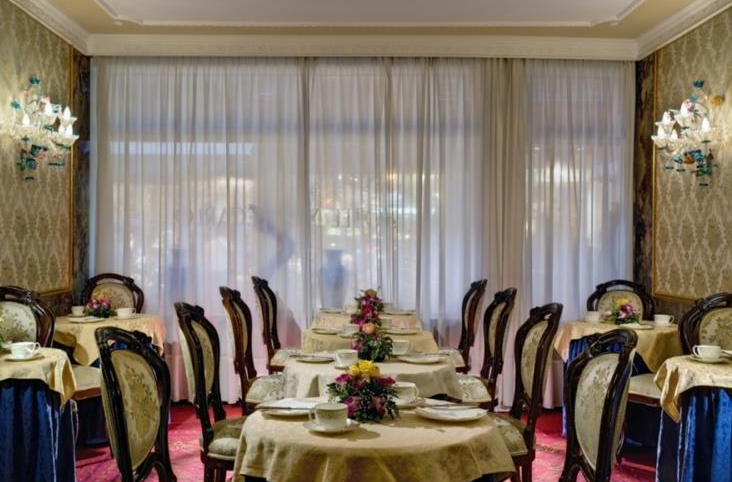 Innenansicht des Speisesaals im Hotel Montecarlo mit elegant eingerichteten Tischen und Stühlen.