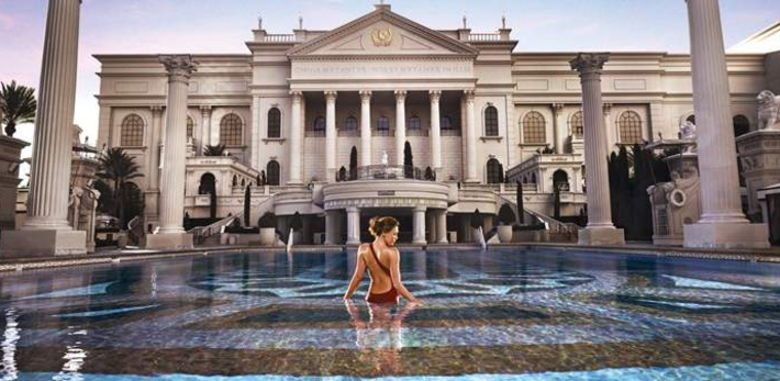 Eine Frau steht in einem runden Pool vor dem Caesars Palace Hotel.
