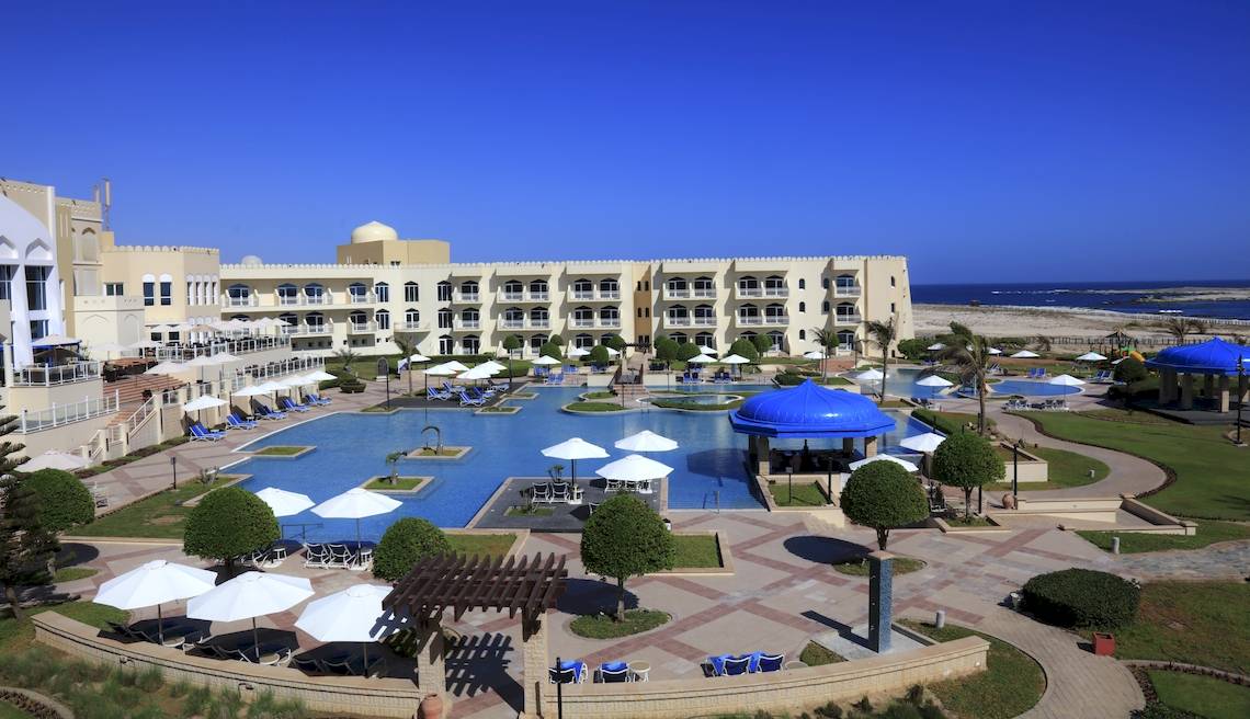 Luftaufnahme des Wyndham Garden Salalah Mirbat Hotels mit Swimmingpools und Liegestühlen.