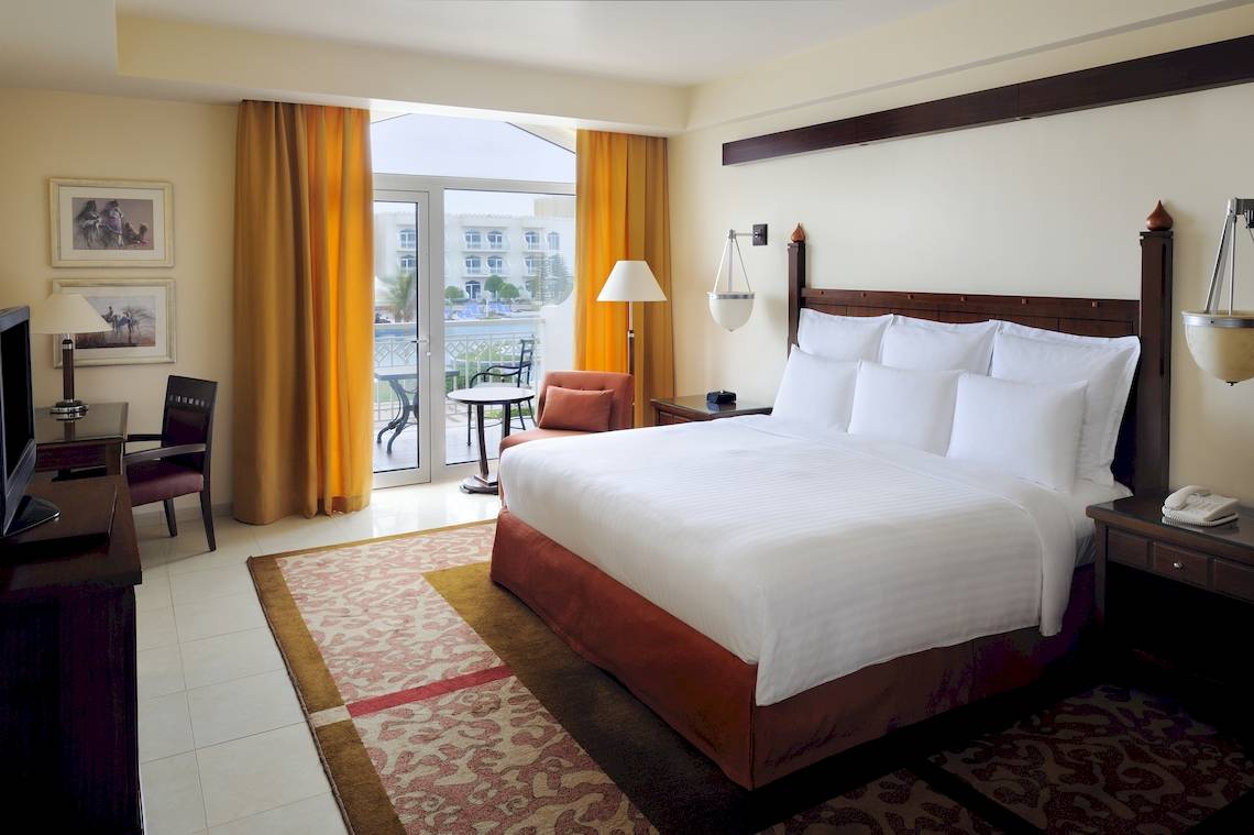 Hotelzimmer im Wyndham Garden Salalah Mirbat mit Doppelbett, Schreibtisch, Fernseher und Balkon.