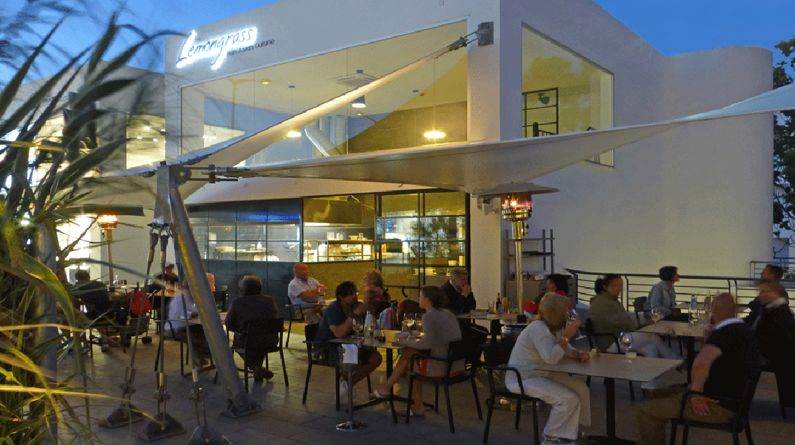 Gäste sitzen bei Tischen auf der Terrasse des Lemongrass Hotels bei Nacht