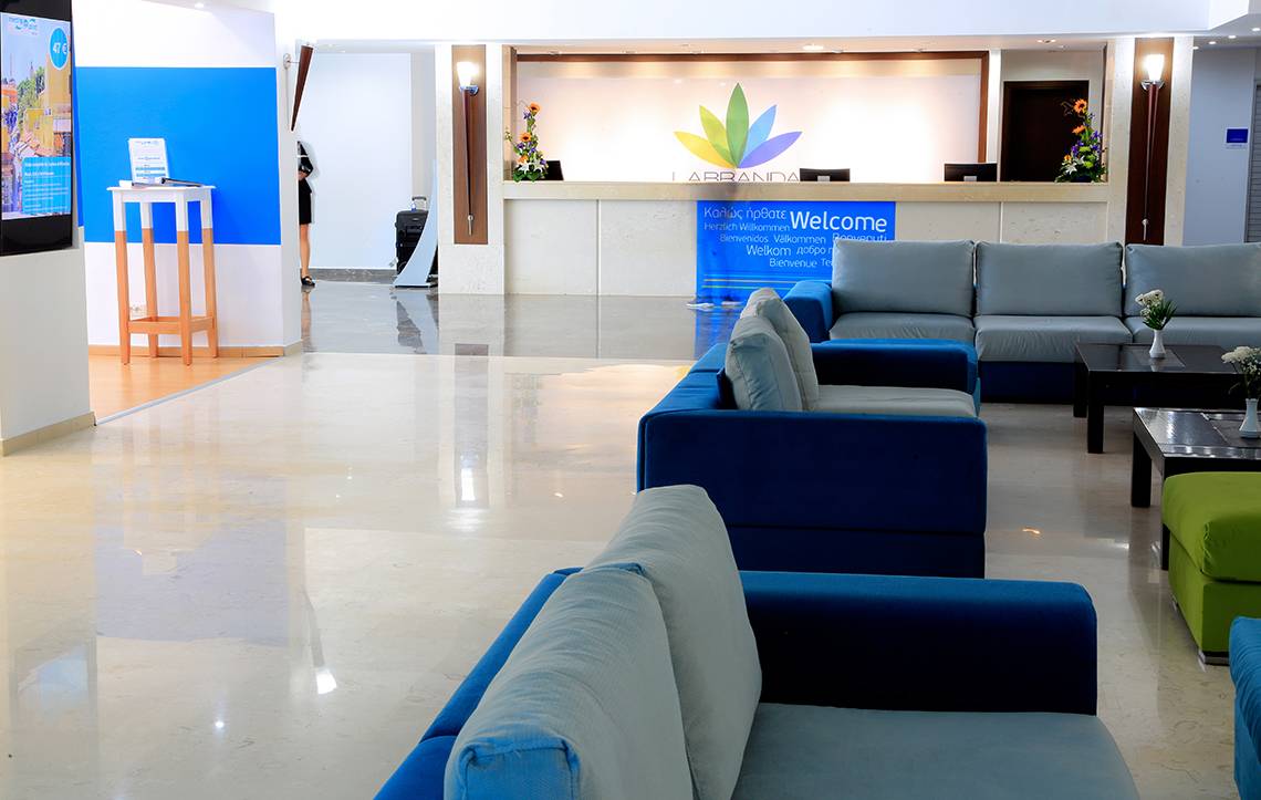 Lobby des Blue Bay Beach Resort mit Sofas, Empfangstresen und Willkommensschild.