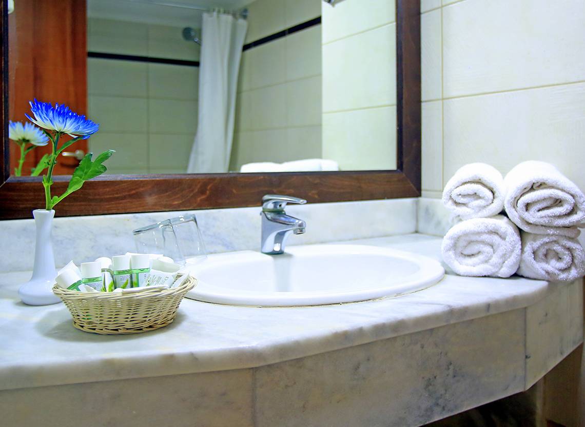 Badezimmer im Blue Bay Beach Resort mit Waschbecken, Spiegel und Handtüchern.