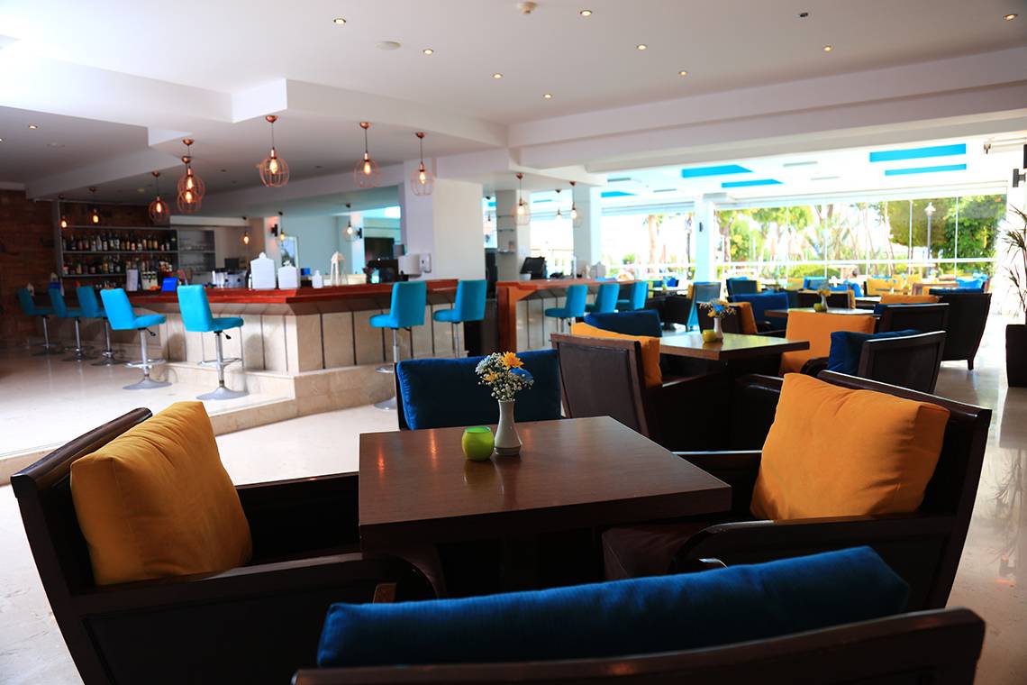 Interieur des Blue Bay Beach Resort Hotels mit Bar, Tischen und Stühlen.