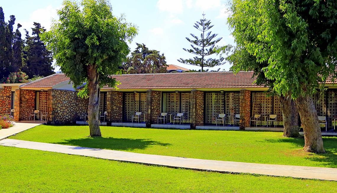 Außenansicht des Blue Bay Beach Resorts mit grüner Rasenfläche und Bäumen.