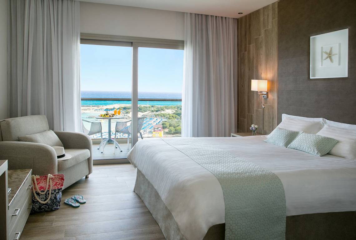 Zimmer im Asterias Beach Hotel mit Blick auf das Meer und einen Balkon.