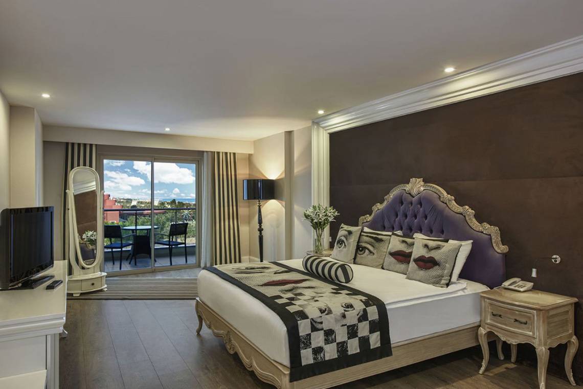 Schlafzimmer des Delphin Imperial Hotels mit großem Bett, Fernseher und Balkon