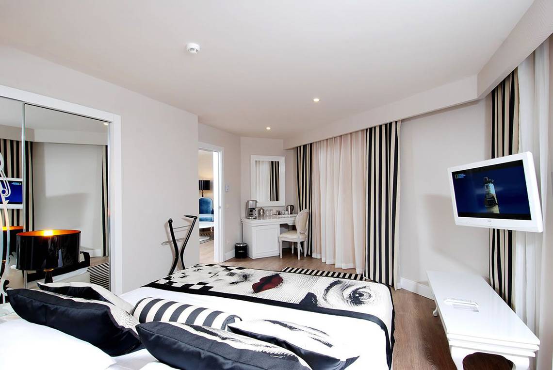 Schlafzimmer im Delphin Imperial Hotel mit Bett, Fernseher, Schreibtisch und Lampe