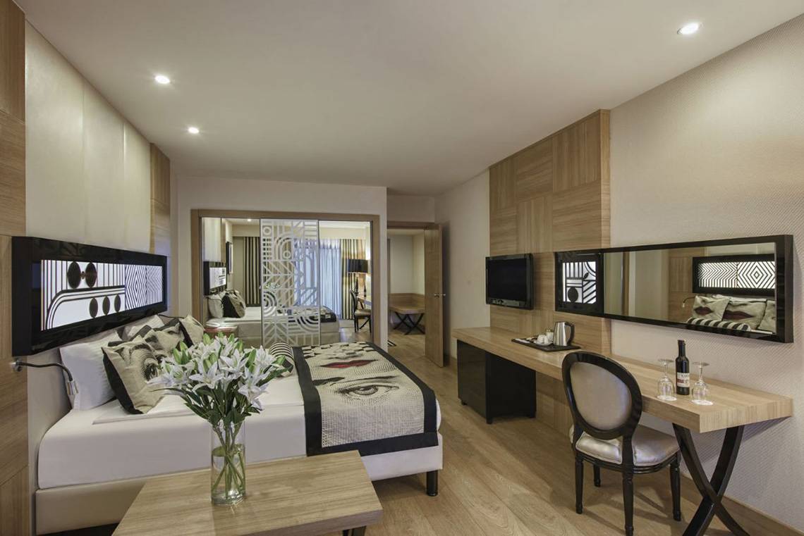 Schlafzimmer im Delphin Imperial Hotel mit Bett, Schreibtisch und Fernseher.
