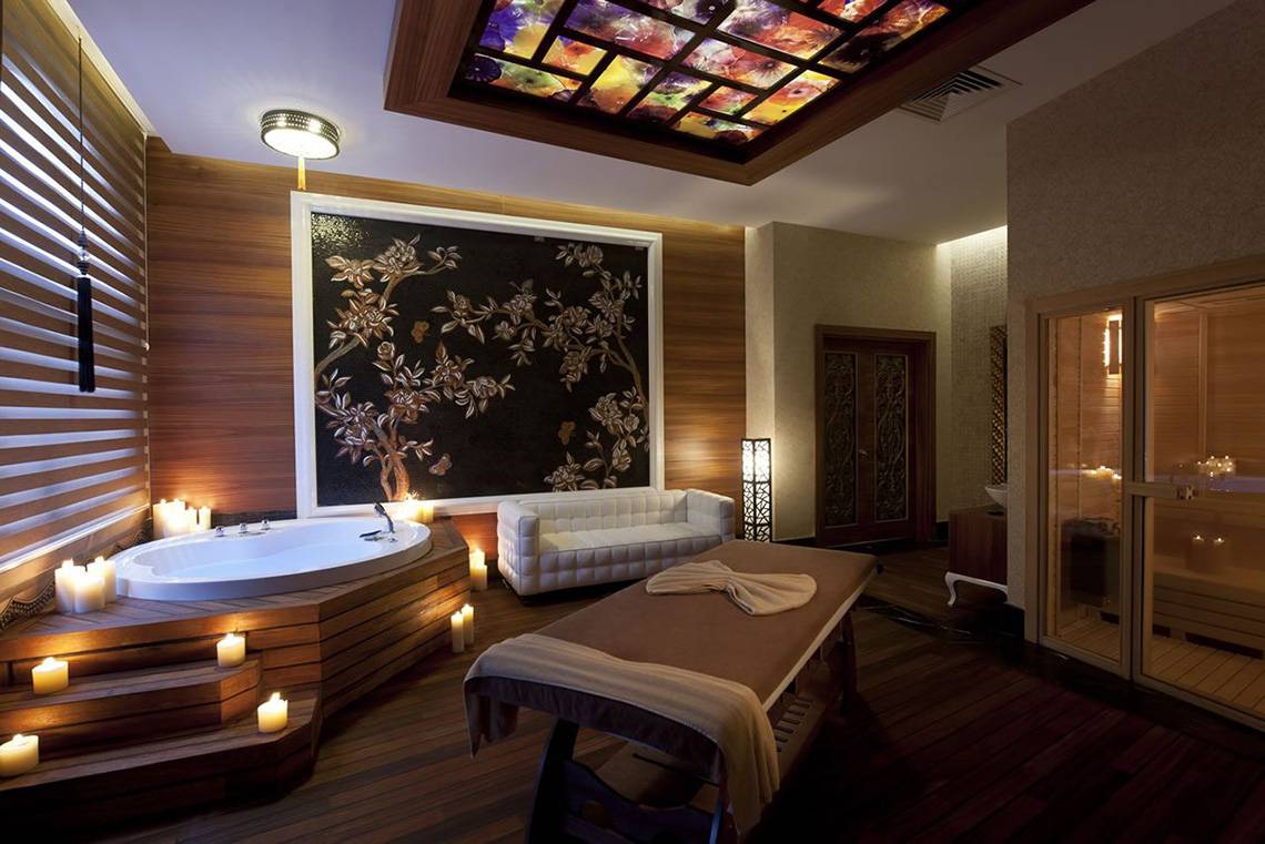 Spa-Bereich im Delphin Imperial Hotel mit Badewanne, Liege, Deko und Beleuchtung.