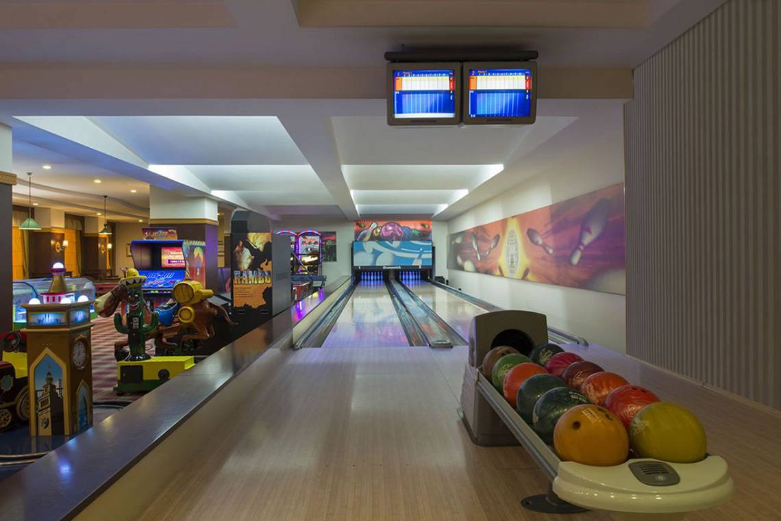 Innenansicht der Bowlingbahn im Delphin Palace Hotel mit Bowlingkugeln und Spielgeräten.