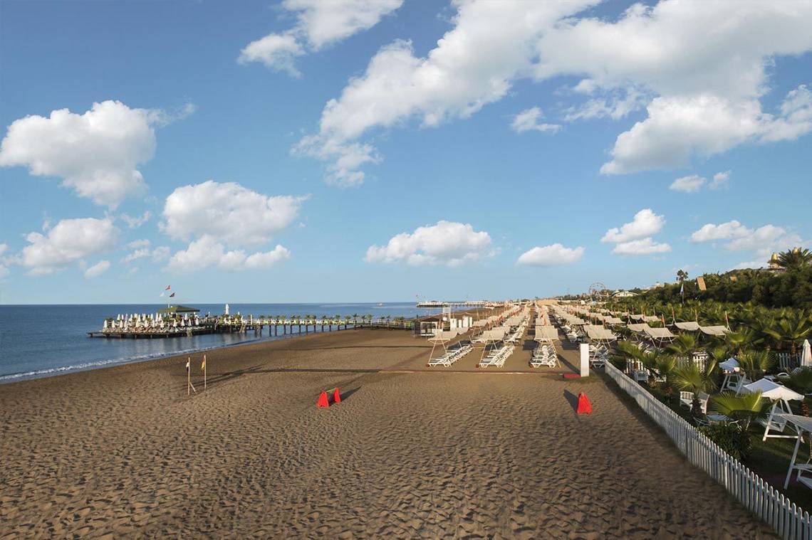 Luftaufnahme des Delphin Palace Hotels Strands mit Sonnenschirmen und Liegen