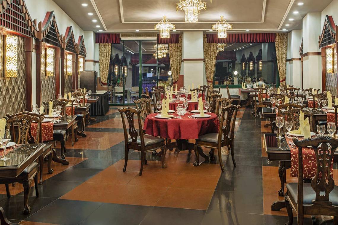 Innenansicht des Restaurants Delphin Palace mit gedeckten Tischen und hängenden Kronleuchtern.