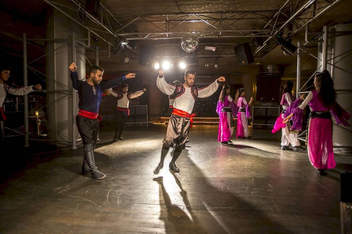 Gruppe von Tänzern in traditioneller Kleidung führt einen Tanz auf der Bühne des Fame Residence Kemer & Spa Hotels auf.