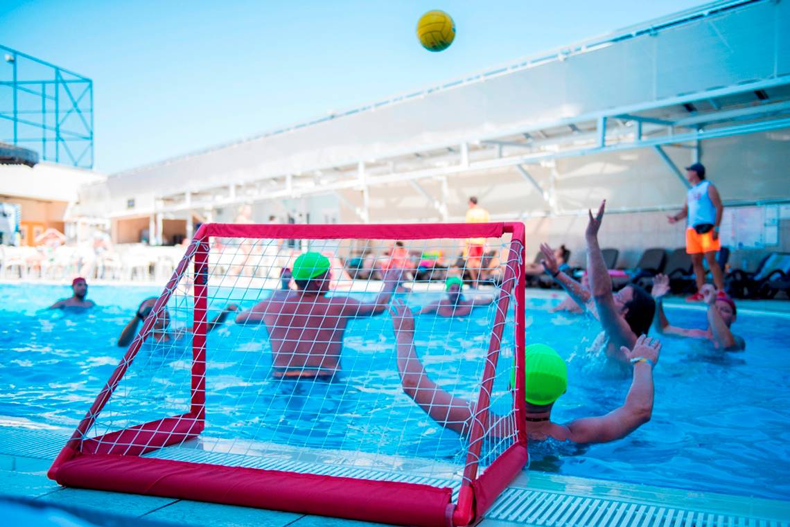 Ein Wasserballspiel im Pool des Side Alegria Hotel & Spa mit Spielern, die den Ball verfolgen.