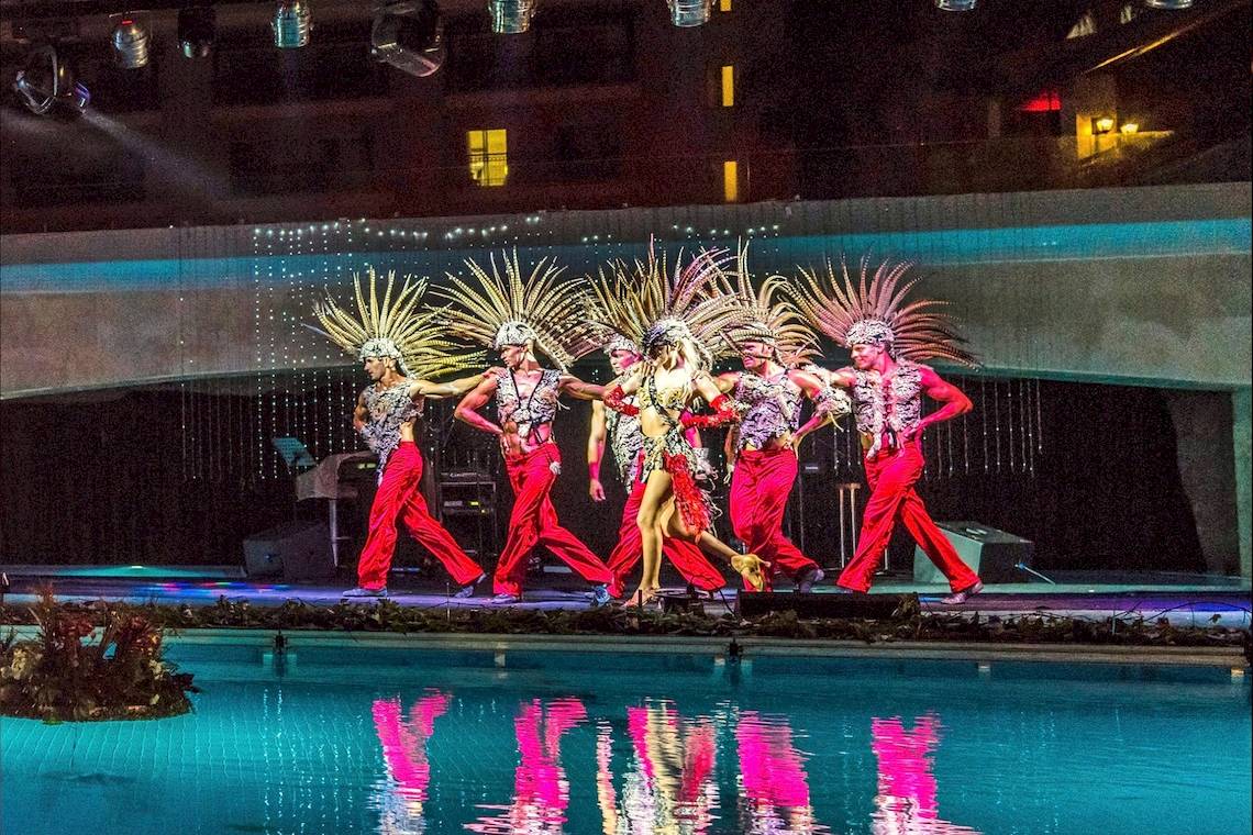 Gruppe von Tänzern in roten Kostümen, die eine Show am Pool des Dobedan Beach Resort Comfort aufführen.