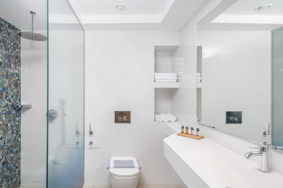 Badezimmer im Lyttos Mare Hotel mit Glasdusche, Toilette und Waschbecken.