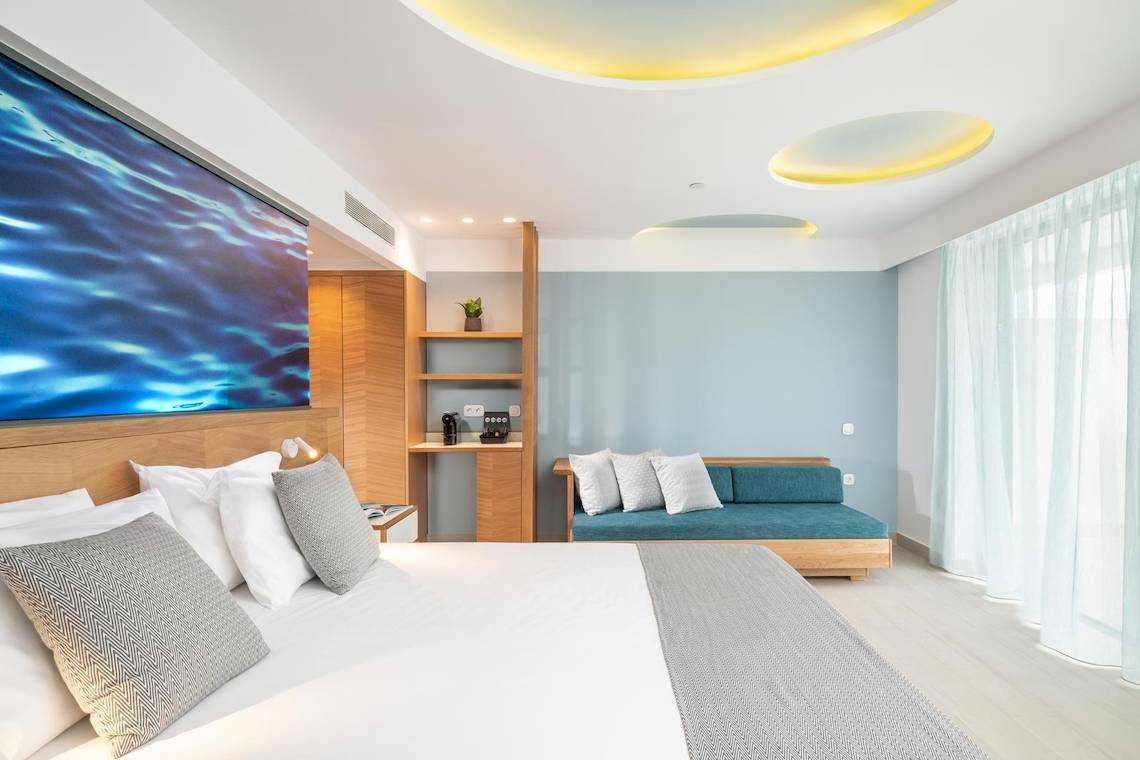 Innenansicht des Schlafzimmers im Lyttos Mare Hotel mit großem Bett, Dekor und Möbeln.