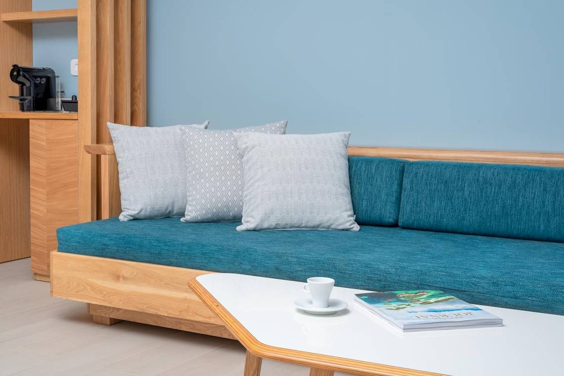 Wohnzimmer im Lyttos Mare Hotel mit Sofa, Kissen und Kaffeetisch.