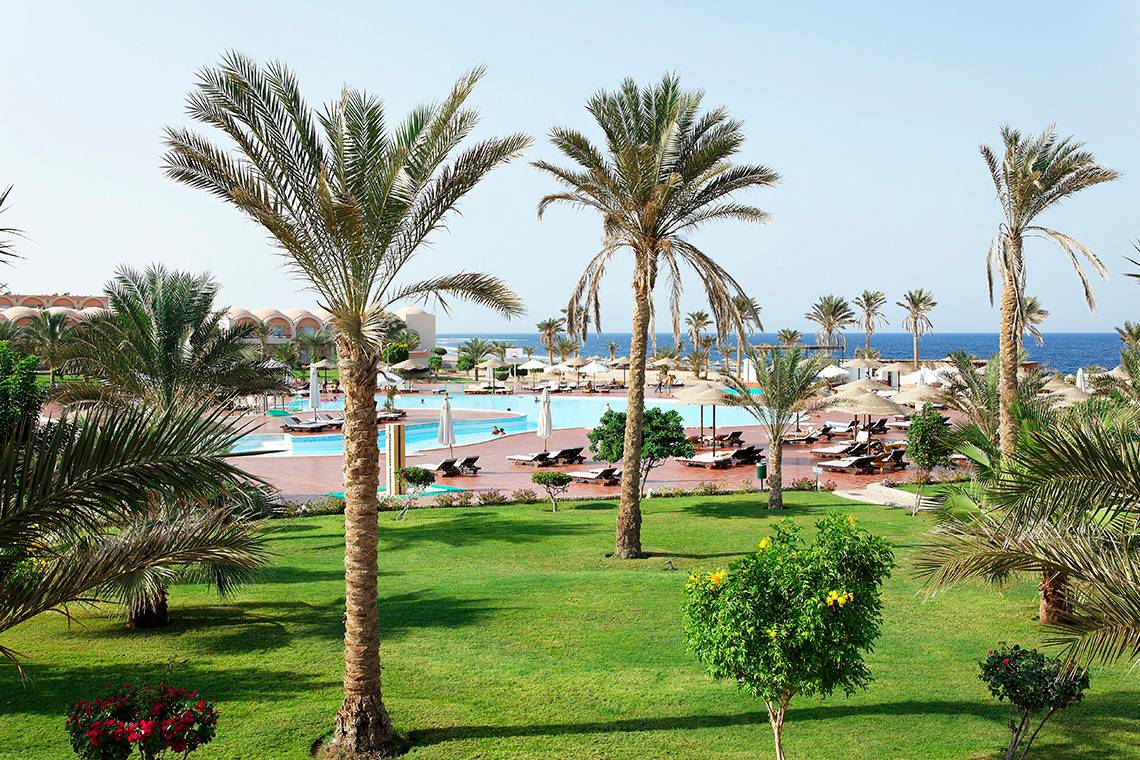 Außenbereich des Three Corners Sea Beach Resorts mit Pool, Liegen und Palmen