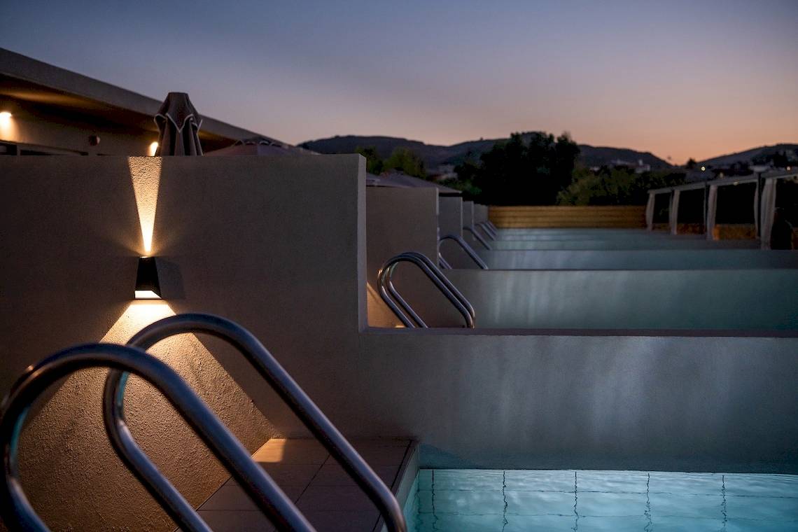 Nachtansicht des Swimmingpools des CHC Galini Palace Hotels mit eingeschalteten Lichtern und dunklem Himmel.