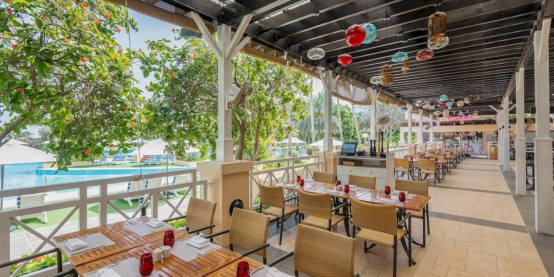 Restaurantterrasse des InterContinental Muscat mit Blick auf den Pool und Garten.