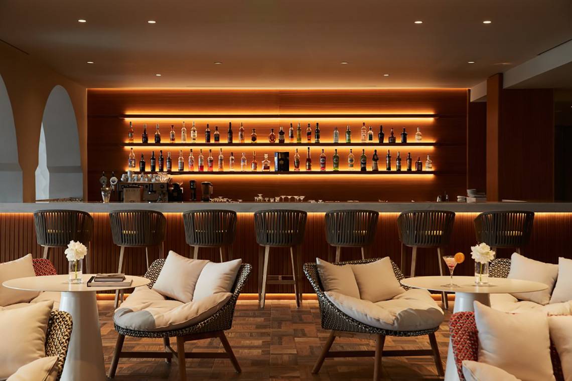 Hotelbar im MarBella Corfu mit Barhockern, Tischen und einer gut bestückten Bar.