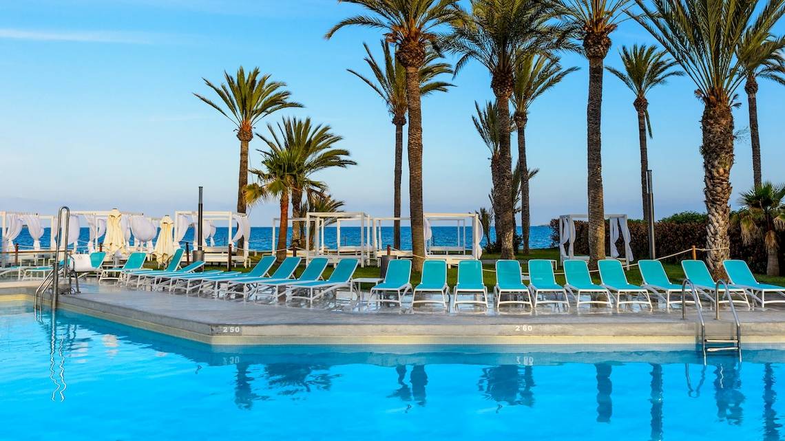 Schwimmbad am Strand des Vibra Algarb Hotels mit blauen Sonnenliegen und Palmen