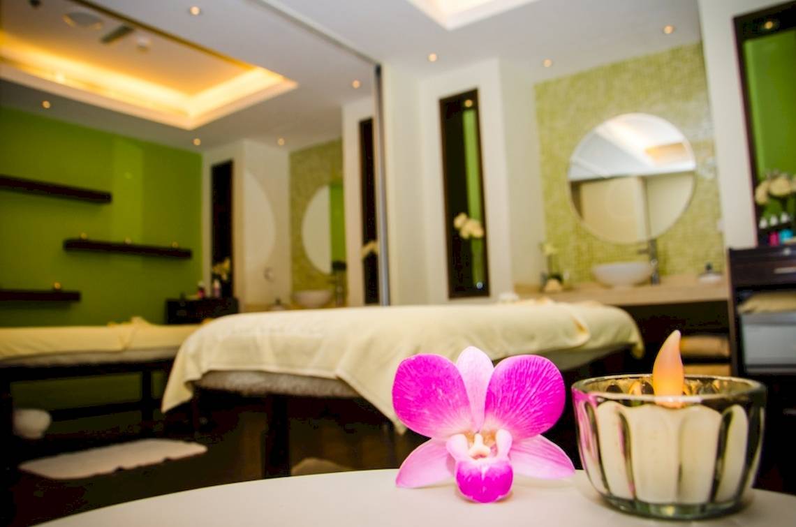 Spa-Behandlungsraum im Khalidiya Palace Rayhaan by Rotana mit Massageliege, Orchidee und Kerze.