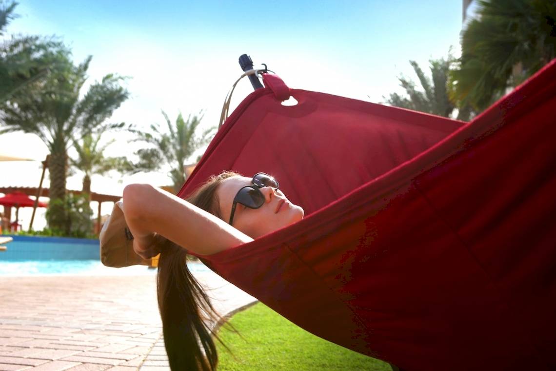 Frau in roter Hängematte am Swimmingpool im Khalidiya Palace Rayhaan by Rotana