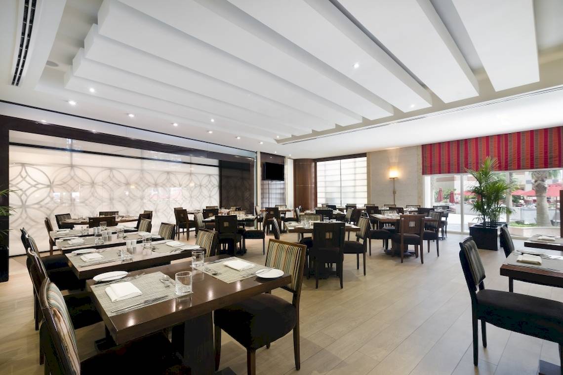 Innenansicht des Restaurants im Khalidiya Palace Rayhaan by Rotana mit eingerichteten Tischen und Stühlen.