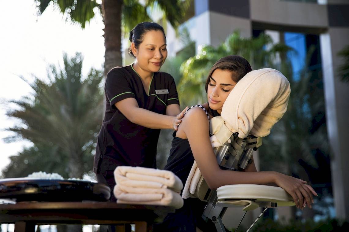 Eine Frau genießt eine Massage im Freien im Khalidiya Palace Rayhaan by Rotana.