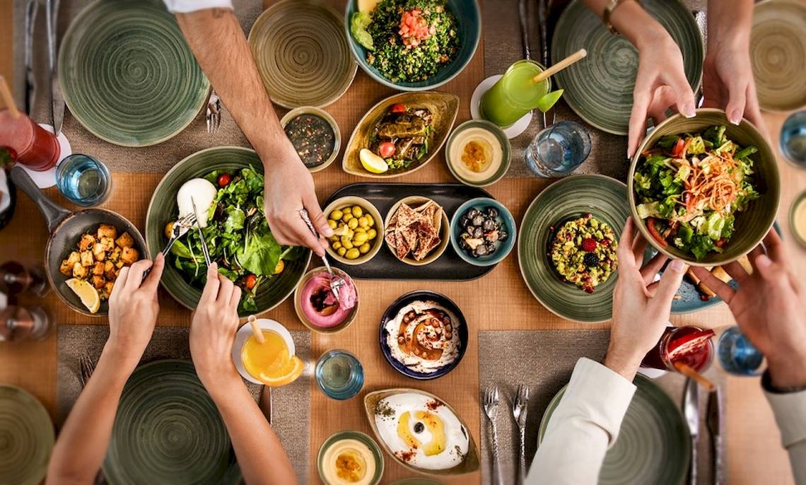 Mehrere Personen essen Salat an einem Tisch im Hotel Khalidiya Palace Rayhaan by Rotana.