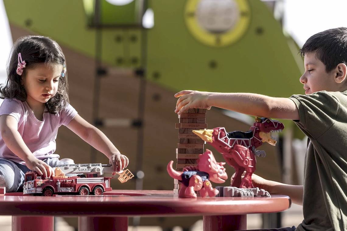 Kinder mit Spielzeug Dinos und Feuerwagen im Freizeitpark