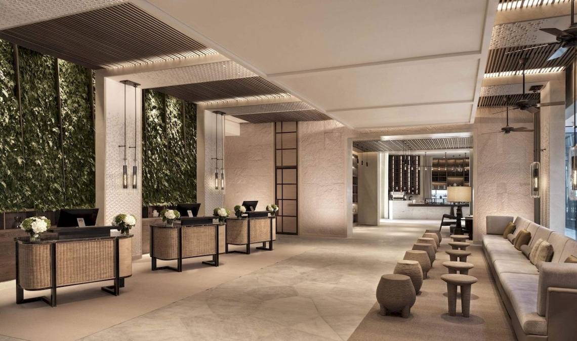 Innenbereich des InterContinental Ras Al Khaimah Mina Al Arab Resort & Spa mit Rezeption, Sofas und Pflanzenwänden.