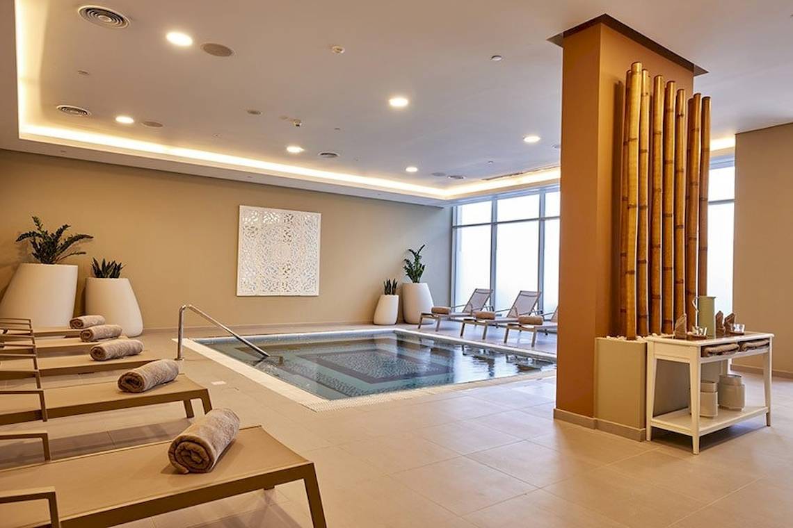 Innenpoolbereich des Riu Dubai Hotels mit Loungestühlen und Pflanzen.
