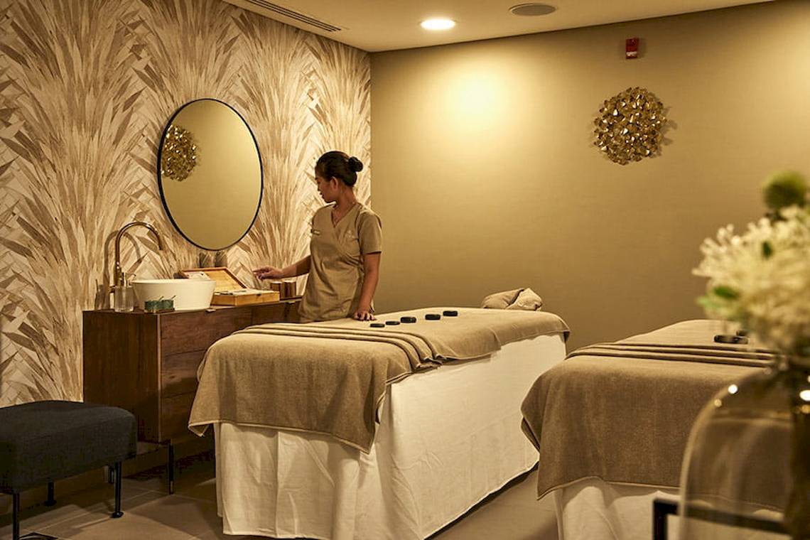 Spa-Behandlung im Riu Dubai mit einer Frau, die einen Massagetisch vorbereitet.