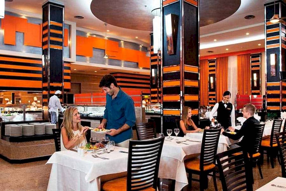 Ein Paar sitzt in einem Restaurant des Riu Palace Bavaro und isst von einem Tablett.